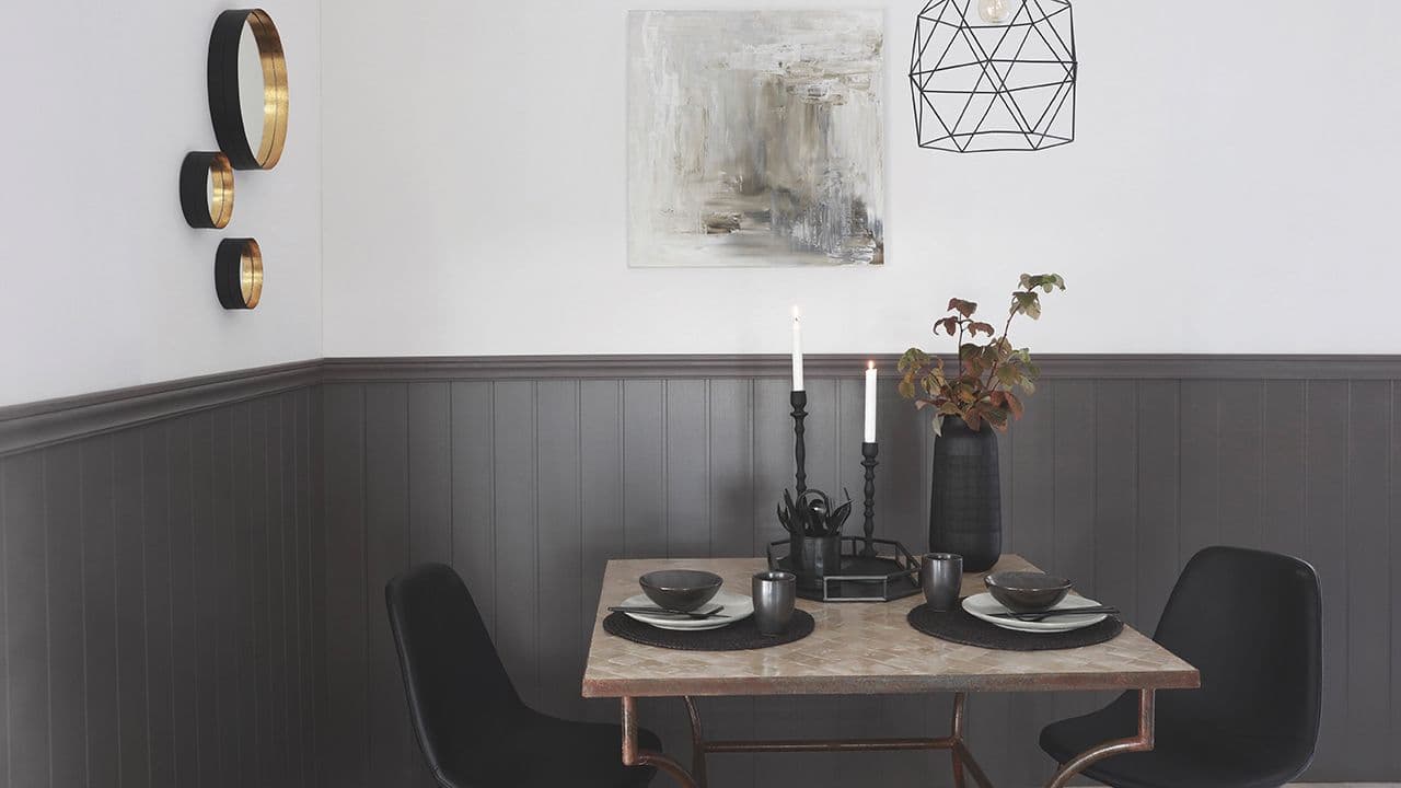 Sort brystpanel i spisestue laget av lister og veggplater.