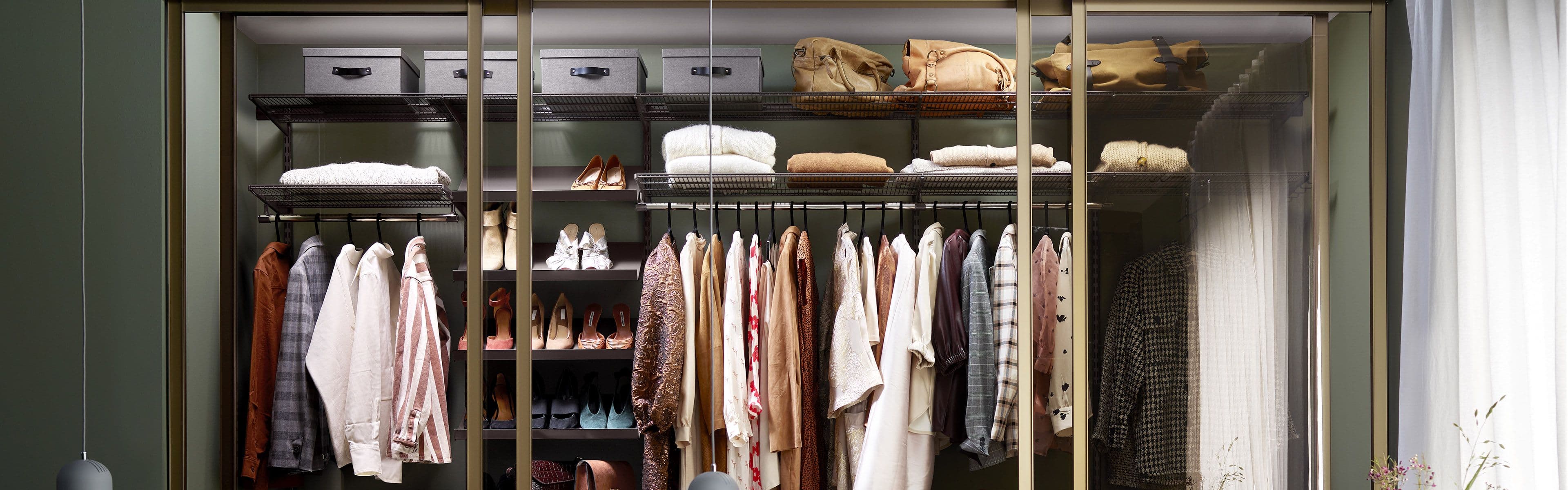 Skyvedørsgarderobe med åpne dører i grønt soverom.