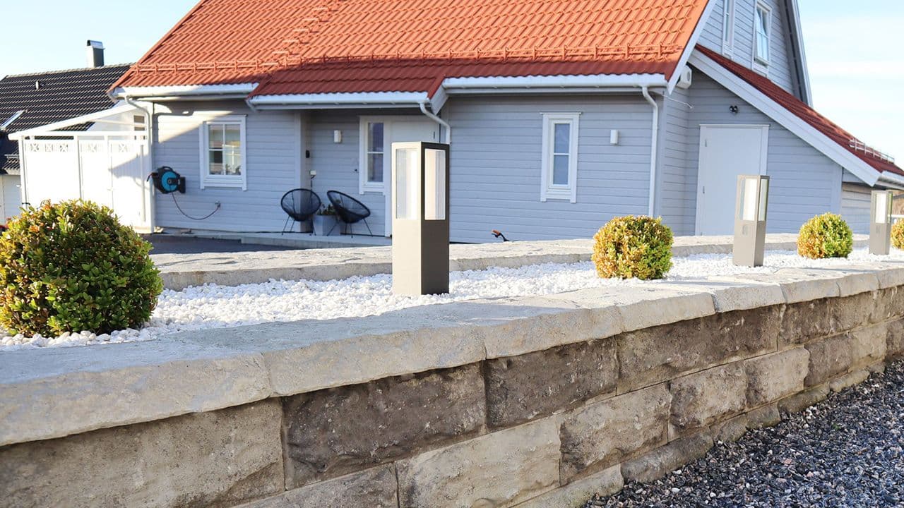 Hvit Dekorstein i opphøyd blomsterbed på mur.