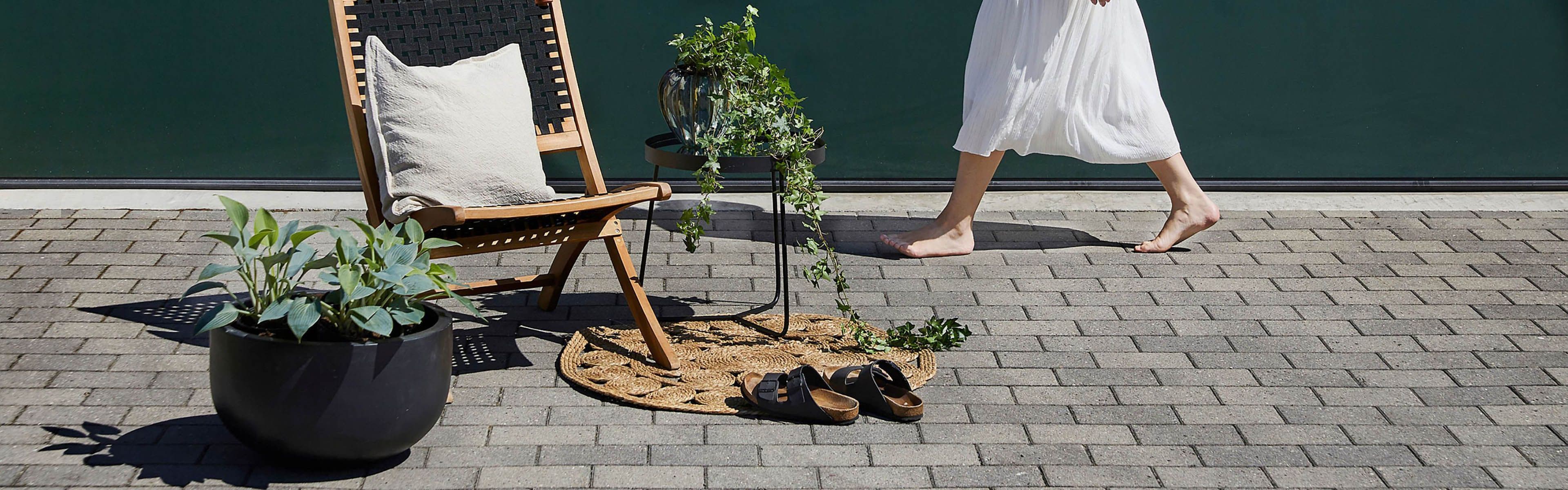 Belegningsstein og møbler med en kvinne som går forbi i bakgrunnen i hvit kjole.