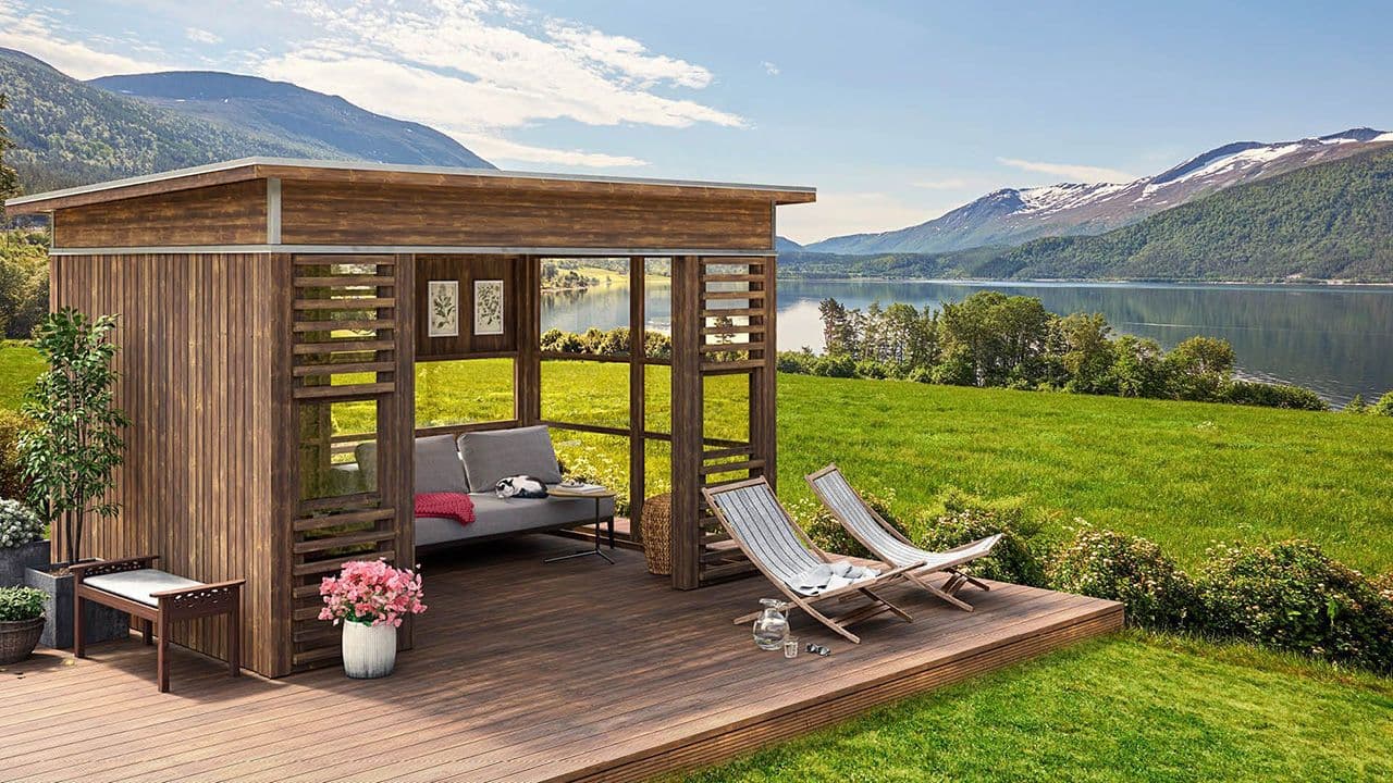 Hagestue byggesett med vinduer og stor platting.