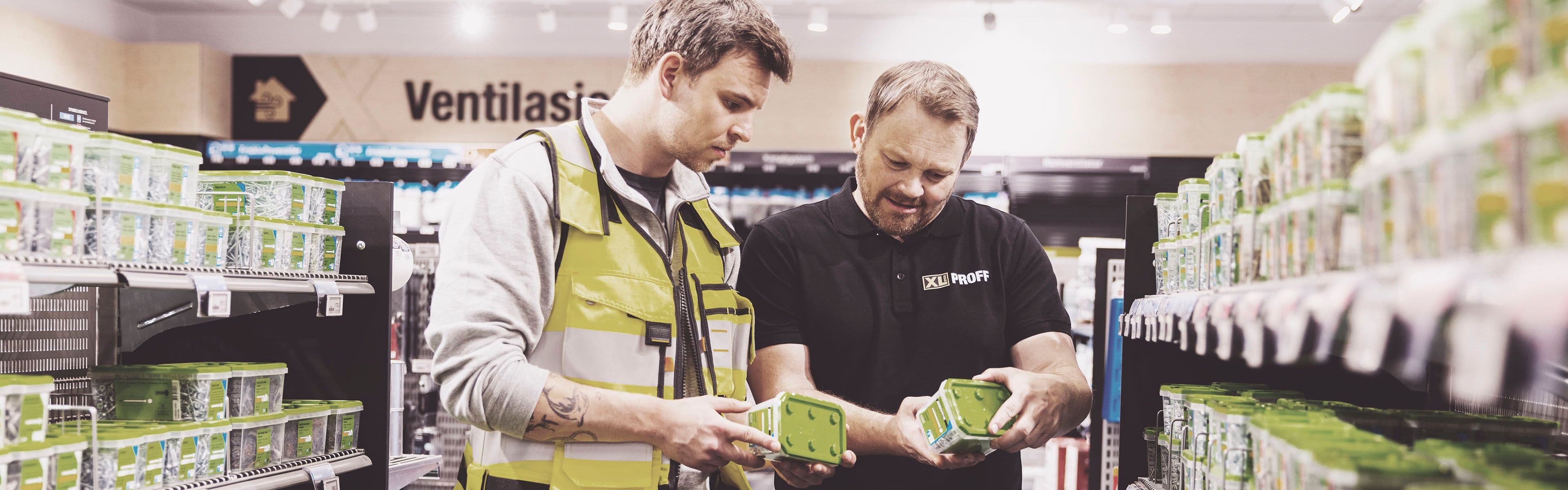 Håndverker og XL-BYGG-ansatt i butikk som ser på produktnyheter