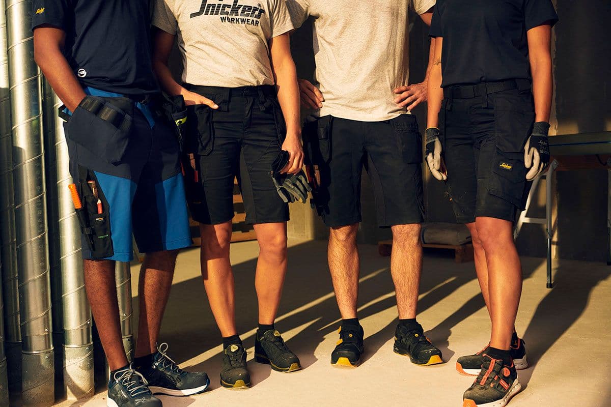 Fire mannlige håndverkere i shorts, hodene er ikke synlige