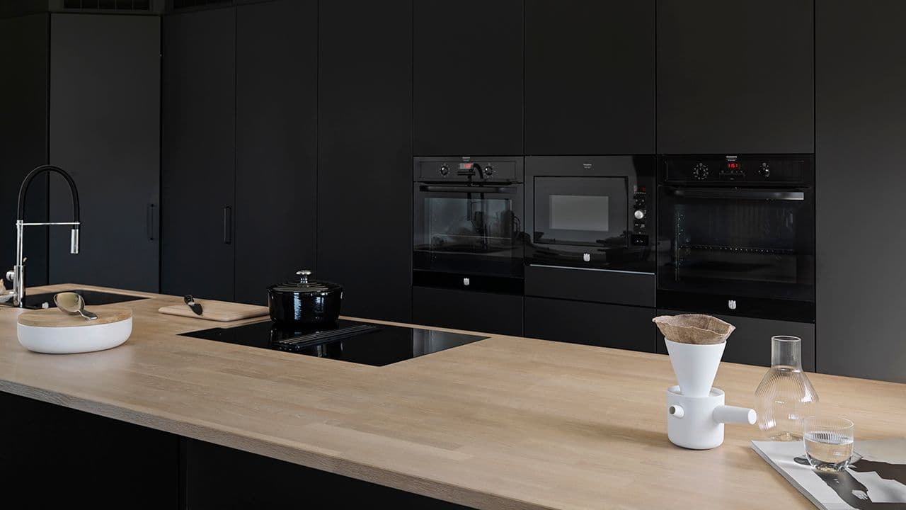 Matt svart kjøkken med lys eik benkeplate i heltre.