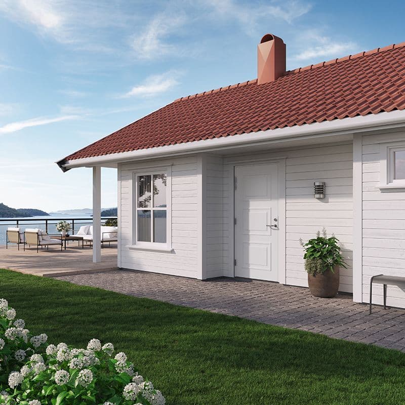 hvit hytte ved sjøen med rødt tak og hvit hyttedør