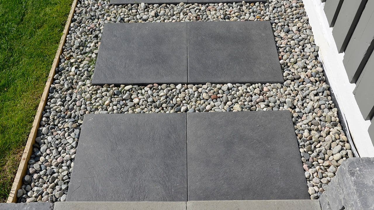 Steinheller som lager hagesti ved plen med grus mellom store steinheller.