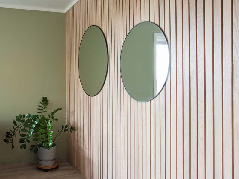 Eikepanel med spiler på vegg i grønn stue.