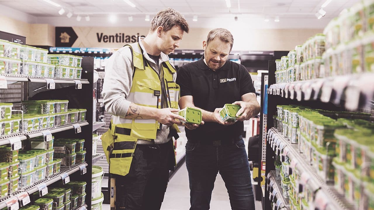 To menn står på XL-BYGG og vurderer ulike skruer.