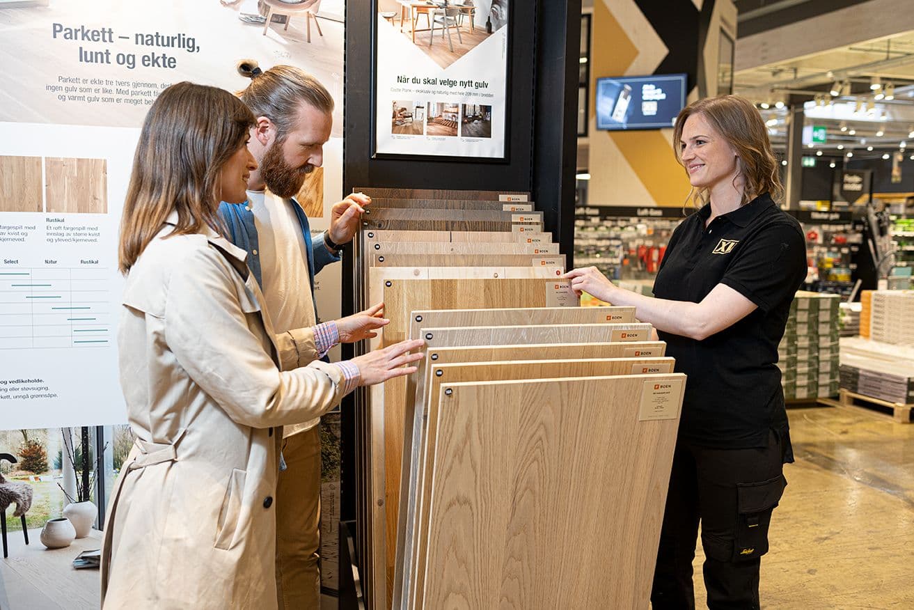 XL-BYGG-ansatt hjelper to kunder å velge gulv