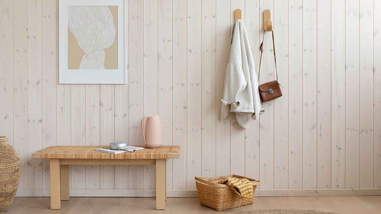 Moderne hytteinteriør med lyst panel i furu og møbler i rotting og lyst treverk.