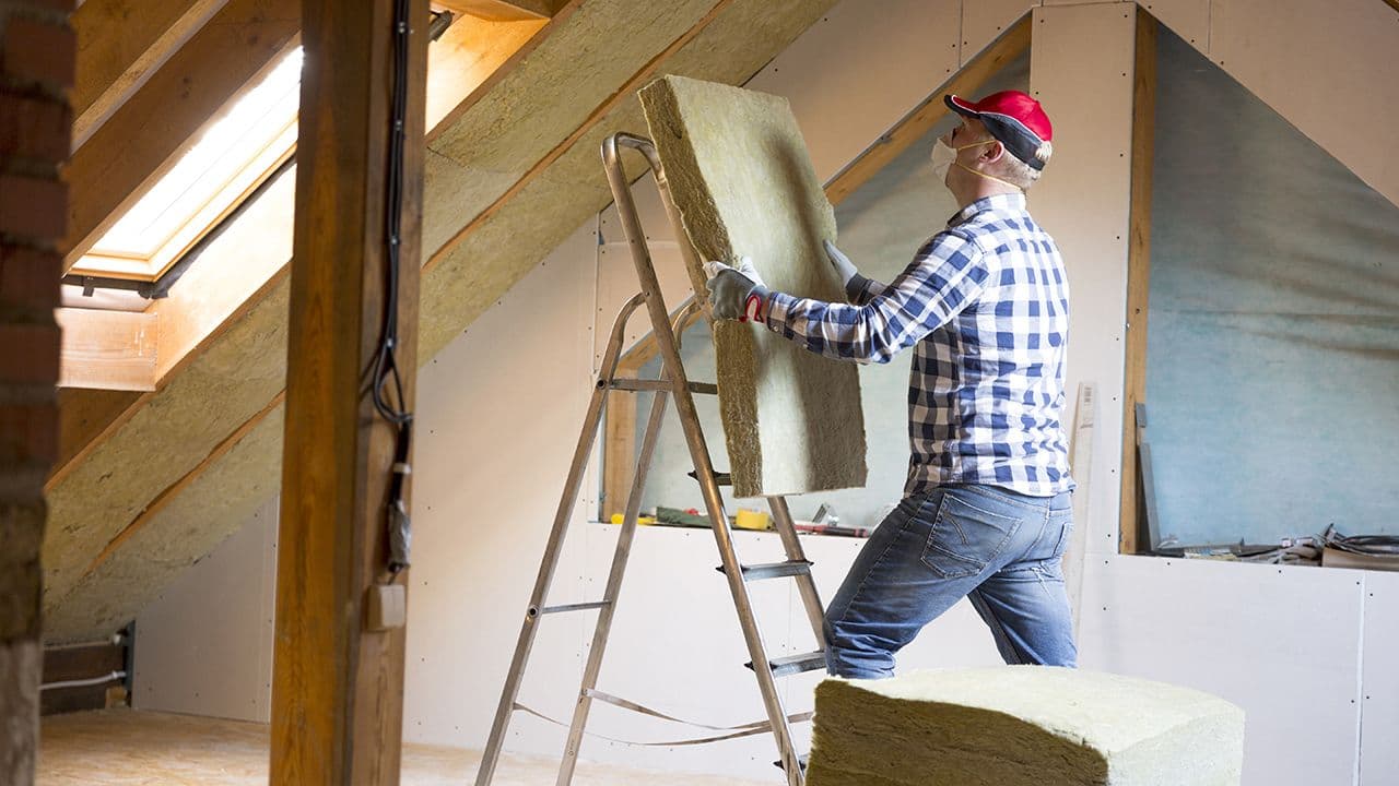 Håndverker som holder på å etterisolere loft.