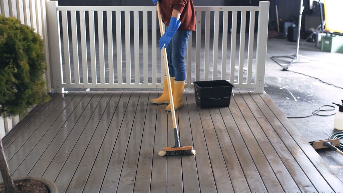 Person som vasker terrassen før den skal oljes.