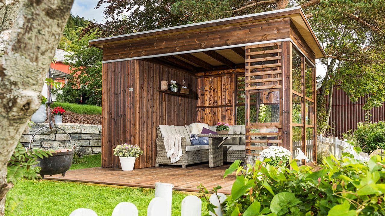 Hagestue byggesett i brunt treverk med vindu.