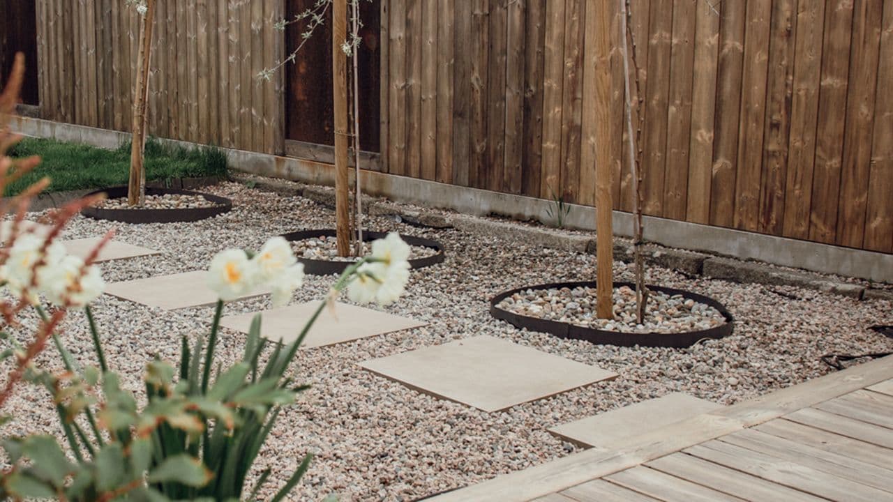 Overgang mellom gressplen og terrasse med dekorstein og steinheller.