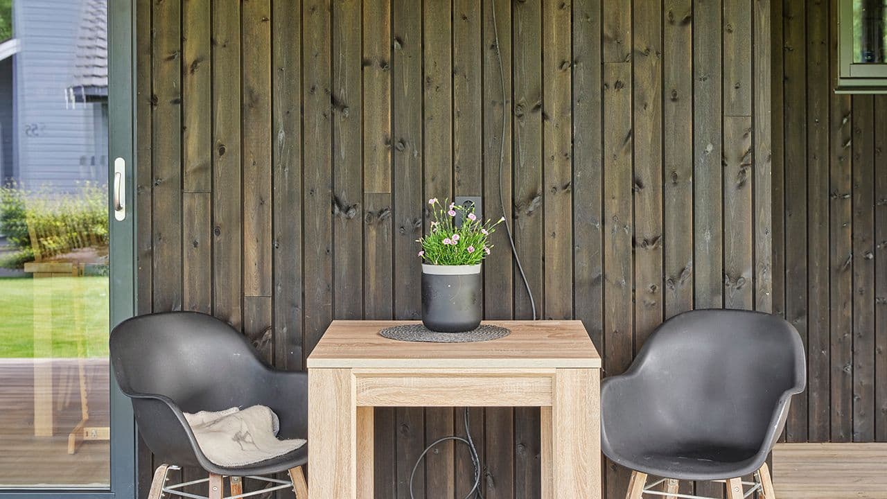 Nærbilde av husets terrasse med MøreRoyal kledning i grå, barbord og to stoler.