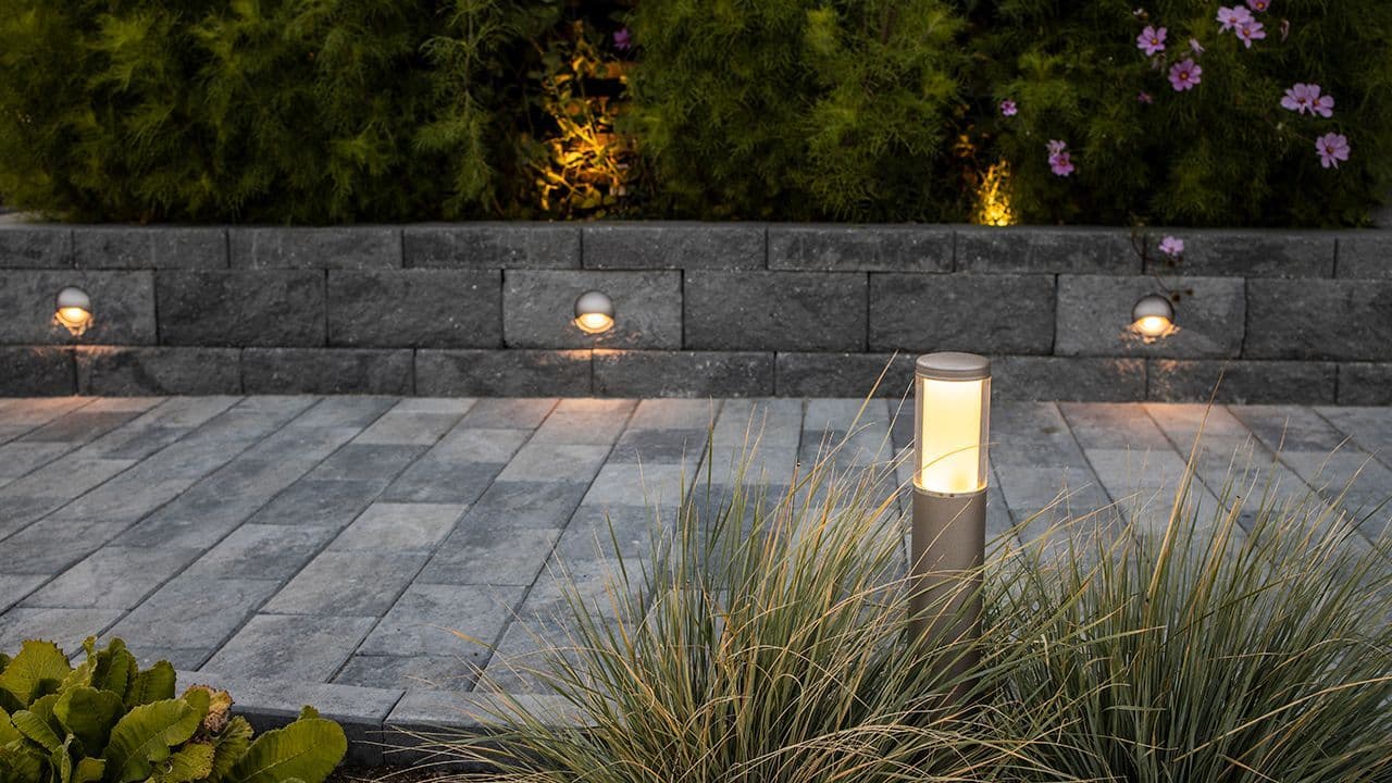 Utebelysning i mur og blomsterbed i innkjørsel.