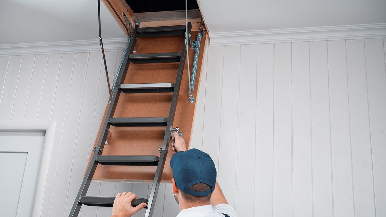 Person som står med åpen loftsluke.