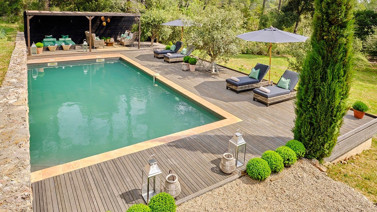 Uteområde med terrasse med basseng, solstoler og pergola.