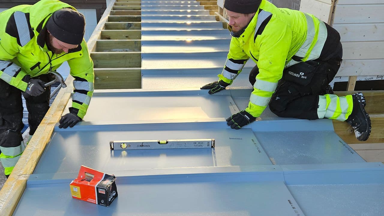 To håndverkere som legger vanntette plater på terrasse.