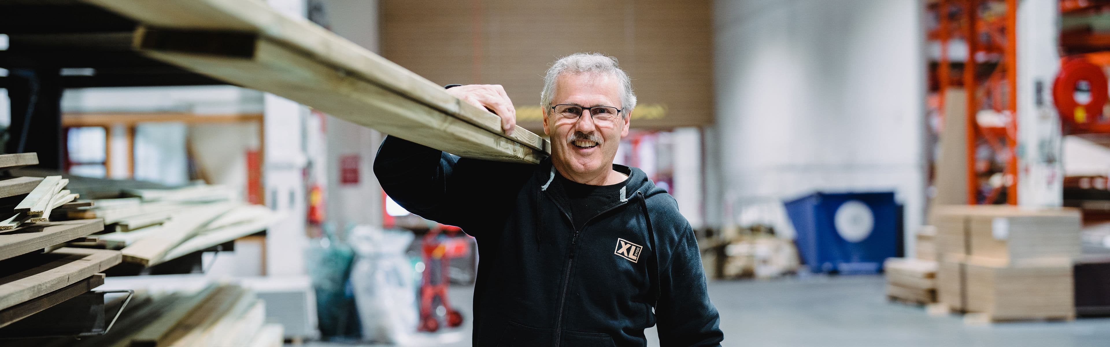 Kvinne ligger på en solseng under en parasoll ved et basseng med grå terrassegulv.