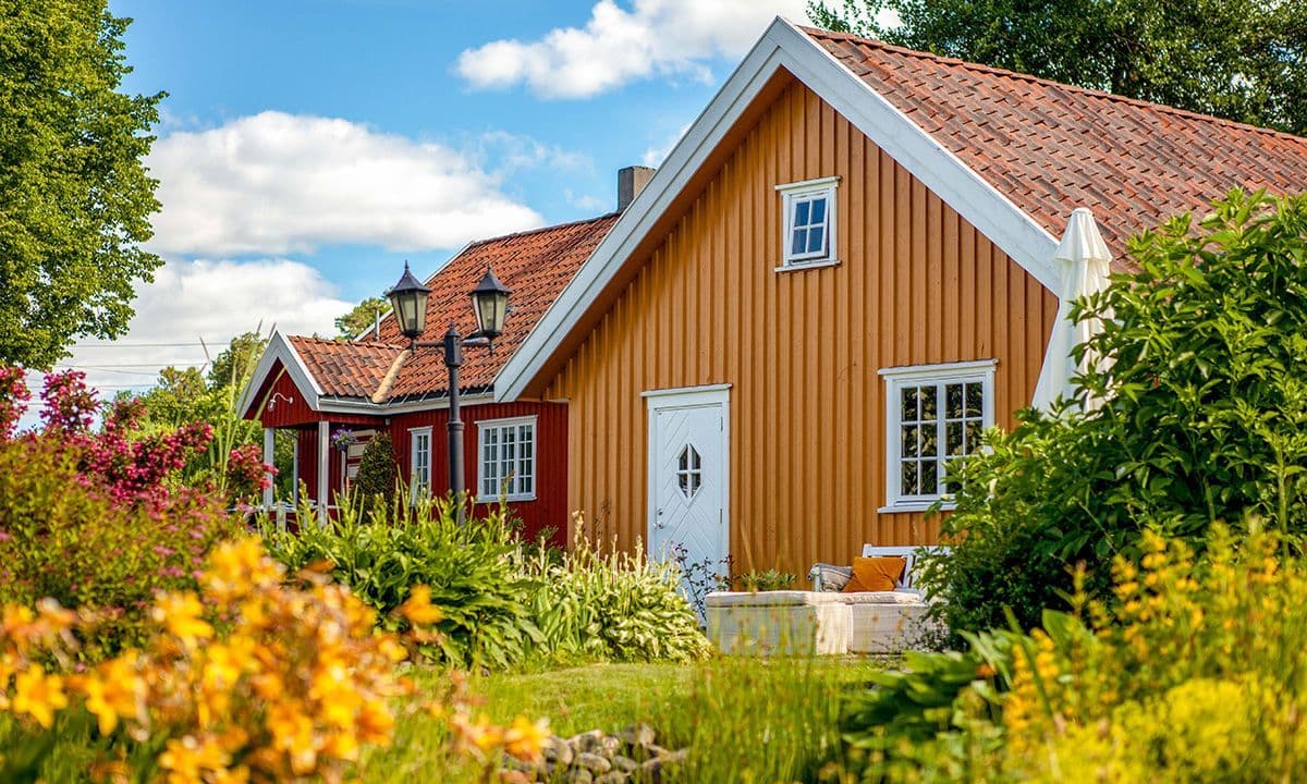 Klassiske trehus i gult og rødt med hvit ytterdør med glassfelt.