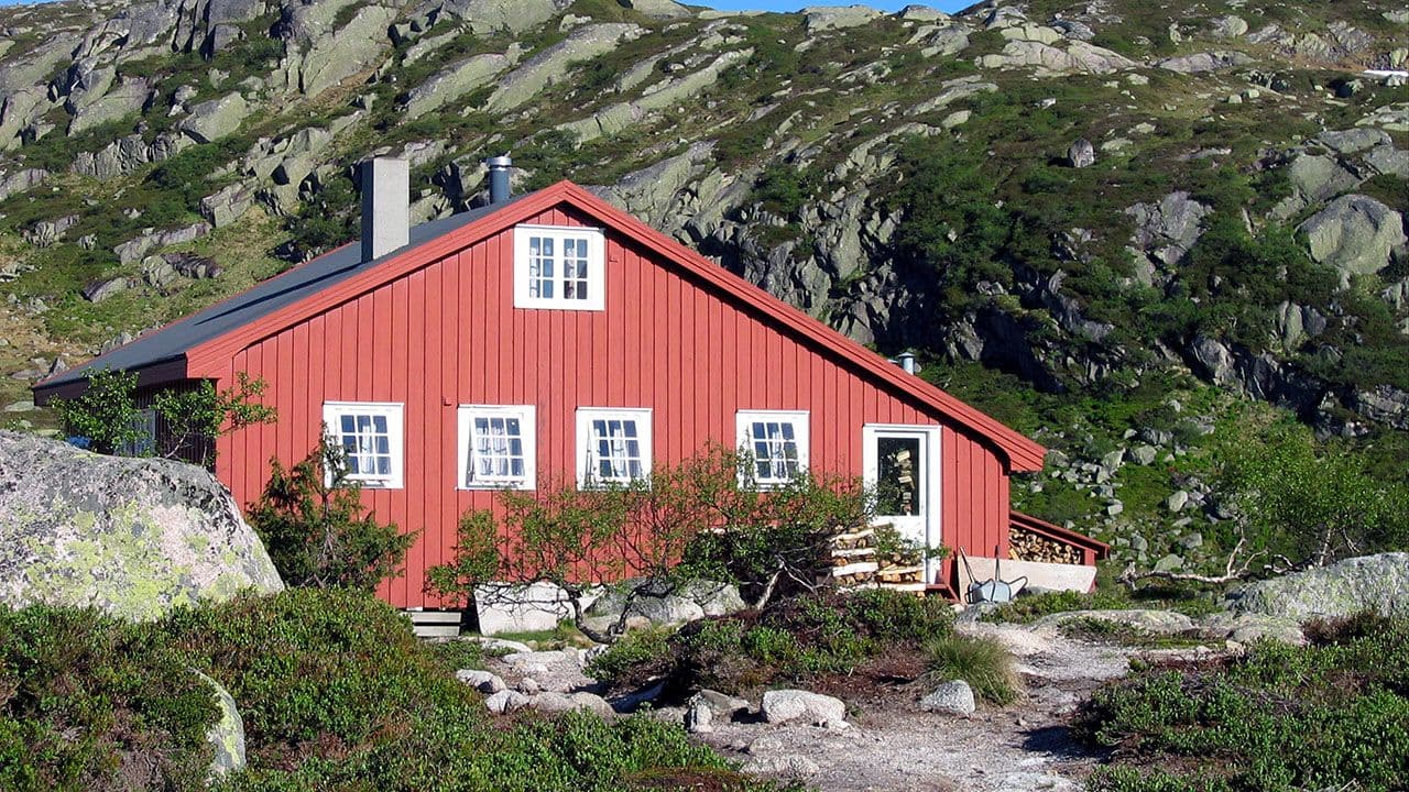 Rød hytte med mange vinduer i fjellandskap i Åseral.