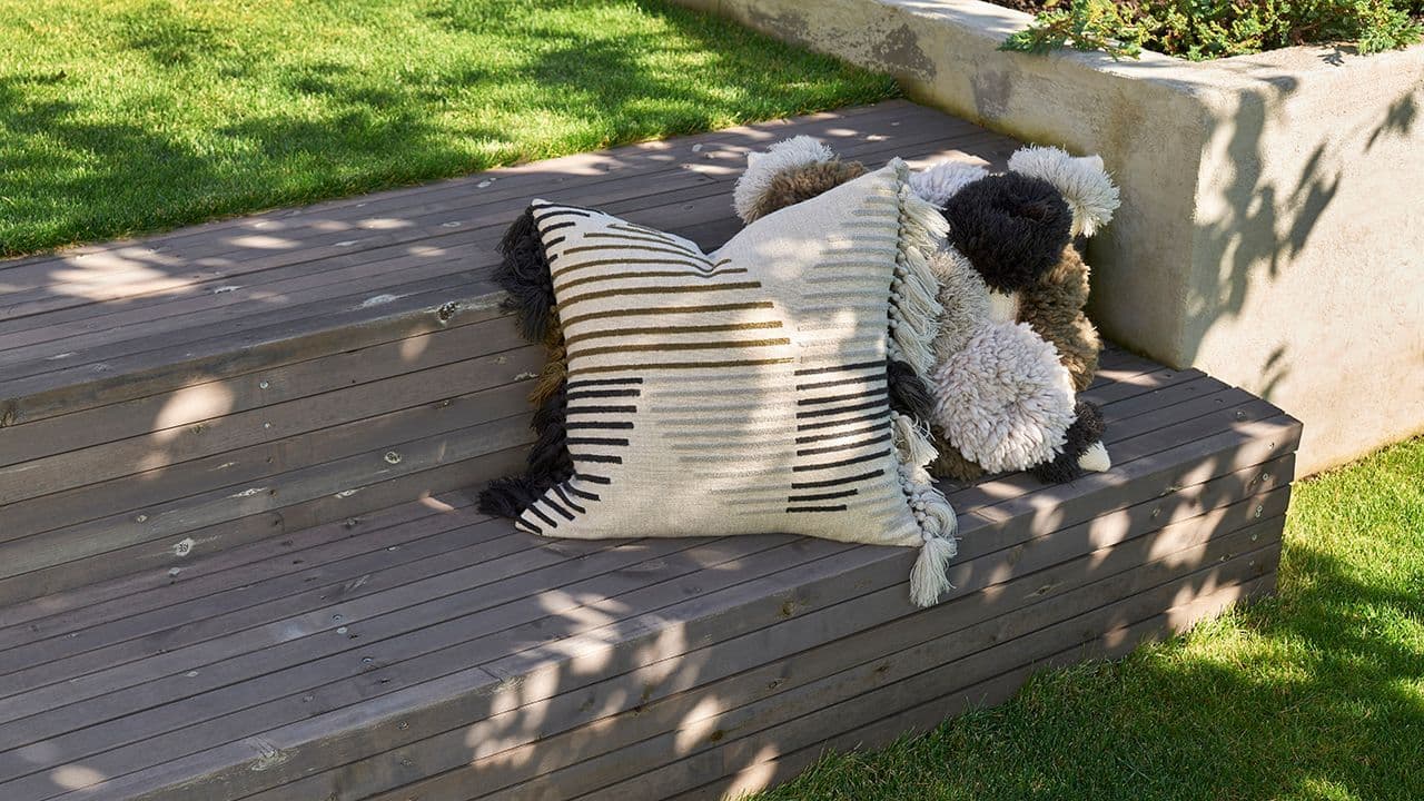 Trapp av terrassebord i hage med puter i.