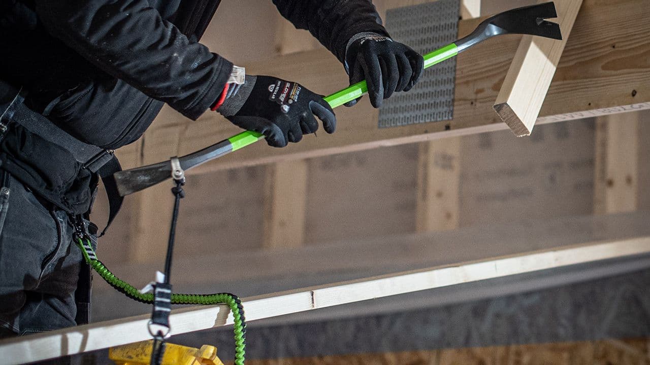 Mann som holder brekkjern som er festet med stropp for verktøysikring.