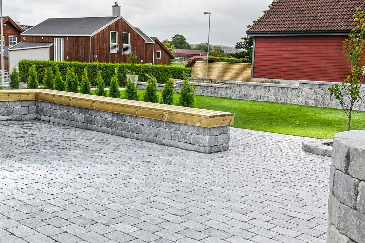 gårdsplass med belegningsstein, støttemur og nyplantet tujahekk