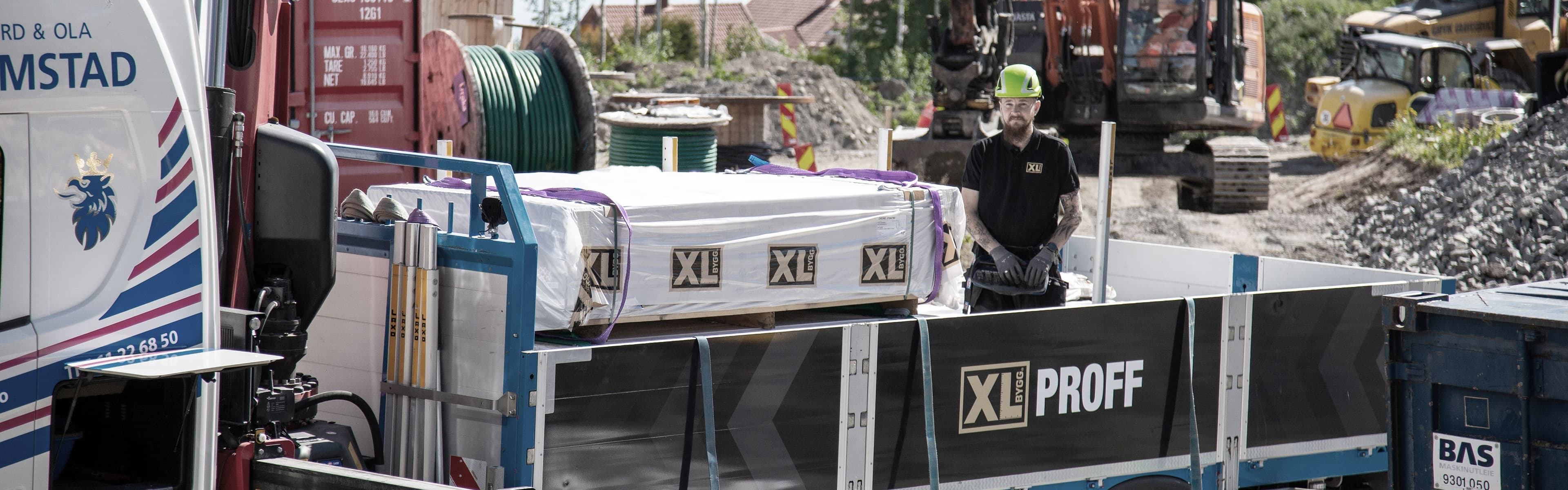 Mann står på en lastebil fra XL-BYGG og styrer en lastekran