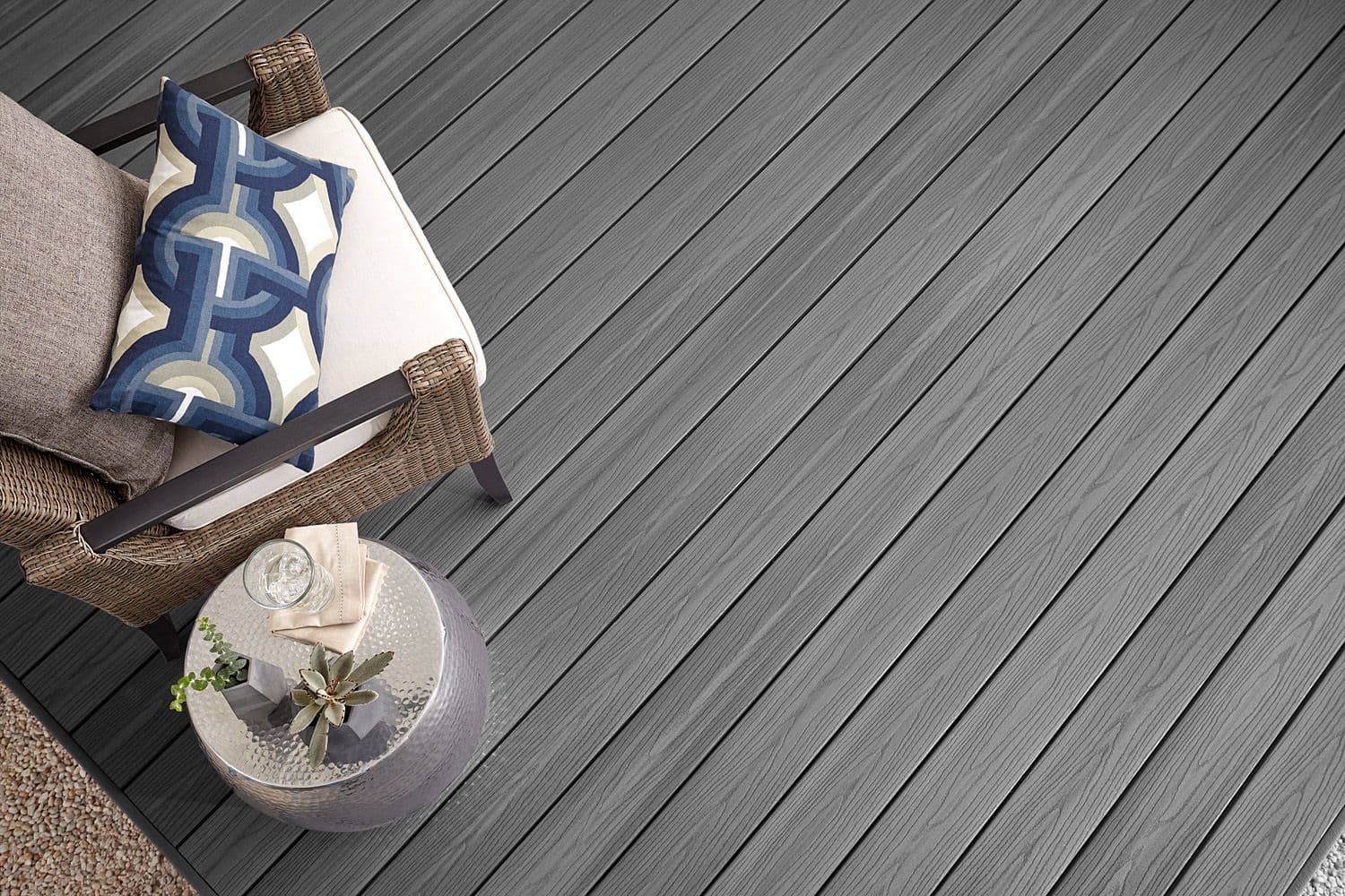 Kurvstol med puter står på kompositt terrasse av typen Fiberon Good Life i fargen Beach House