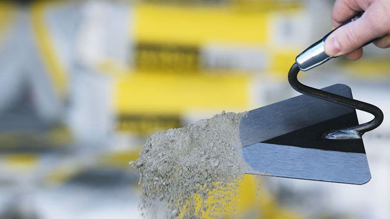 Hånd som holder spade med mørtel.